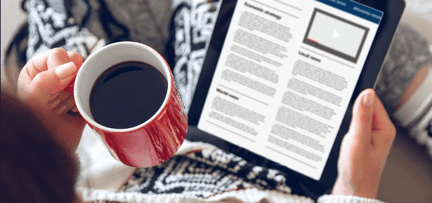 Women reading the news on her tablet with a cup of coffee